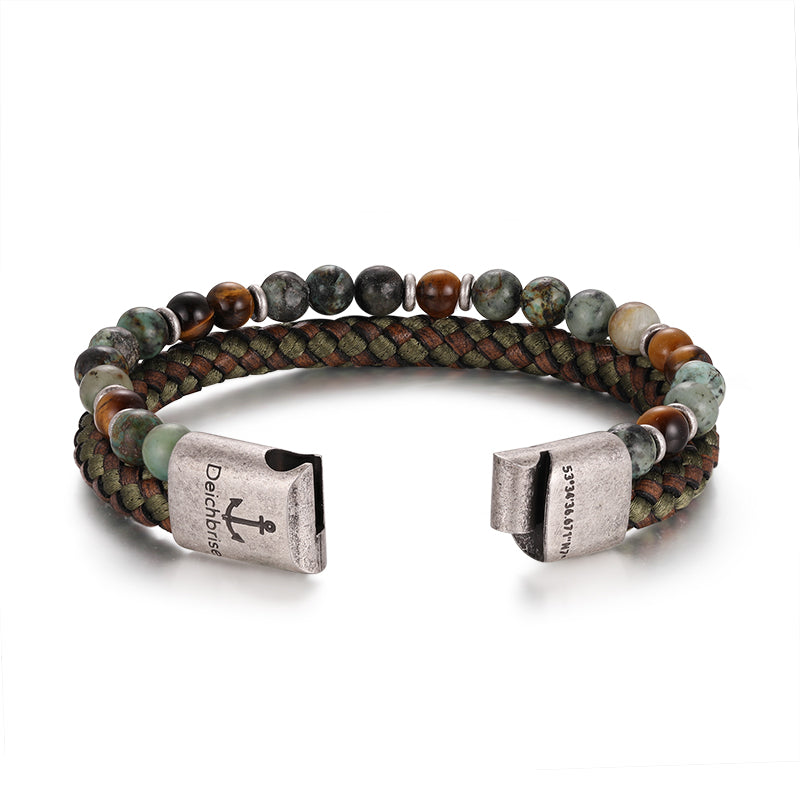 The Armband Playa Beach (Multistrang) features taupe leather, African turquoise, and tiger eye beads in dual rows, finished with silver clasps—one engraved with an anchor and "Beidharsaes.