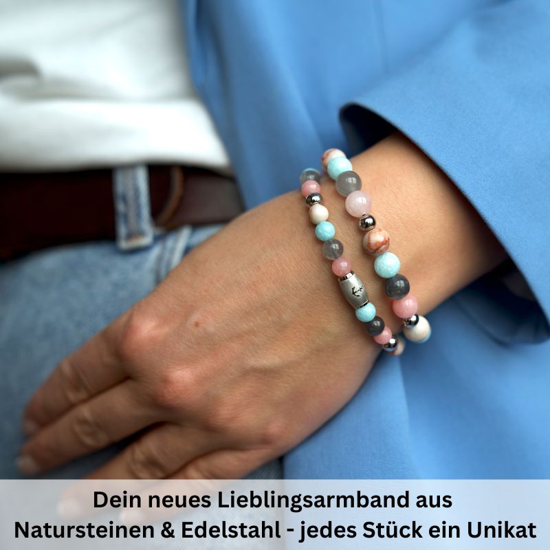A person wearing the colorful Armband Pellworm mit Pink Jade, Quarz-Kristall, Roter Netz Jaspis und Edelstahl-Beads, styled with a blue jacket and white shirt. German text below describes these unique natural stone bracelets.
