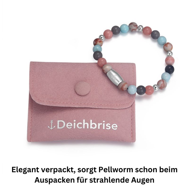 A pink Deichbrise pouch with a multicolored Armband Pellworm aus Pink Jade, Quarz-Kristall, Rotem Netz Jaspis und Edelstahl-Beads. German text: Elegant verpackt, sorgt das Armband Pellworm schon beim Auspacken für strahlende Augen.