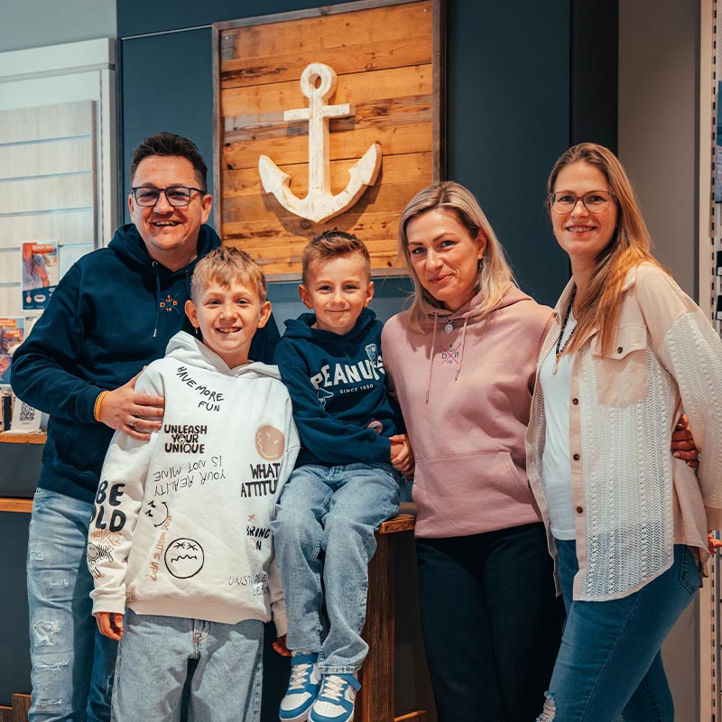 Die Gründerfamilie von Deichbrise mit zwei Kindern vor einem hölzernen Anker