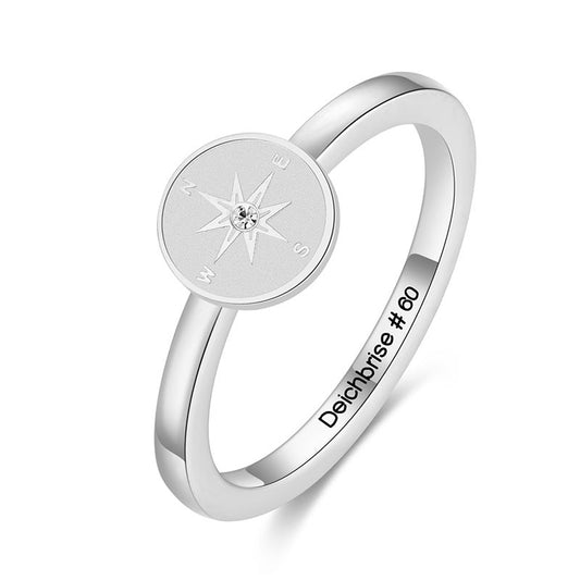 Silberfarbener Ring Kompass mit rundem Kompass-Motiv und kleinem Stein vor weißem Hintergrund
