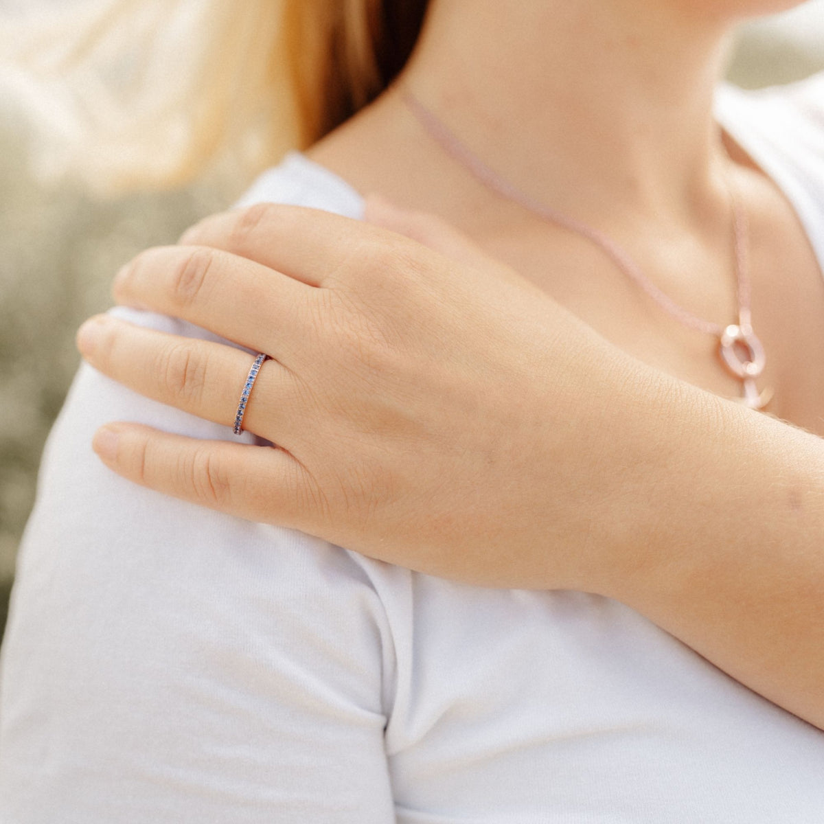Ring Bling Bling mit blauen Steinen an der Hand einer Frau auf der Schulter